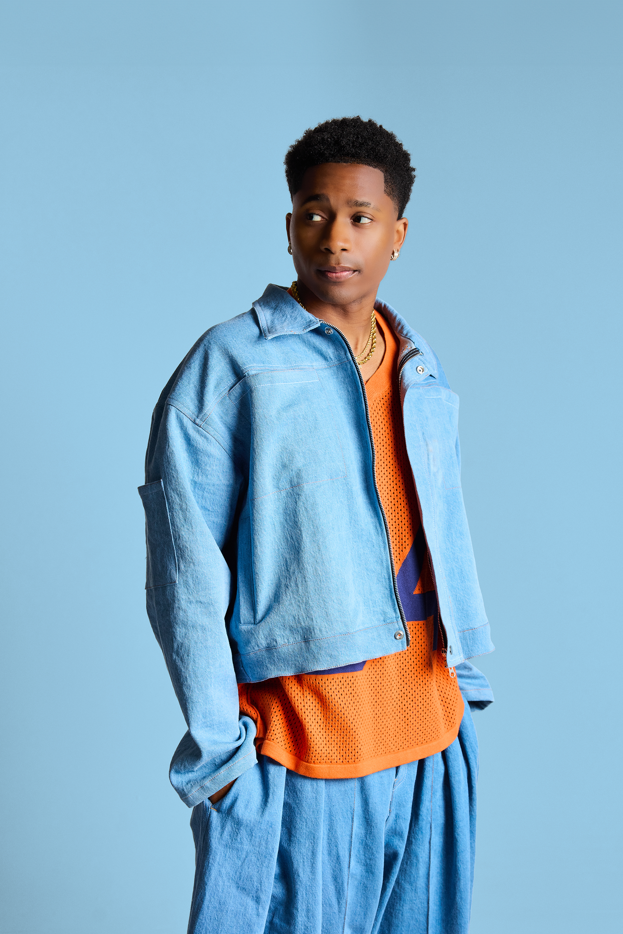 Person wearing a blue jacket and orange shirt against a light blue background