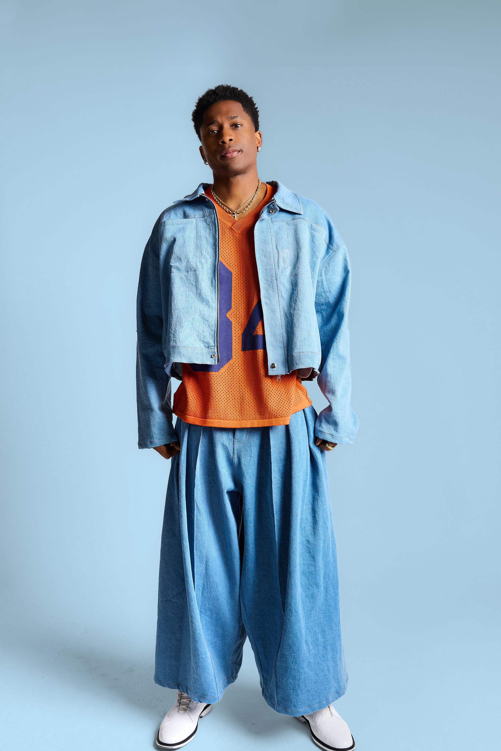 Person wearing a blue jacket and pants with an orange shirt on a light blue background